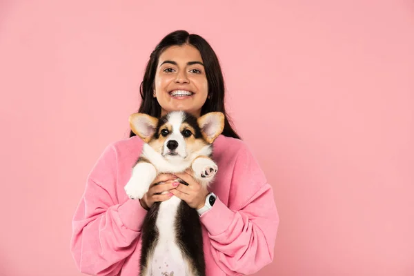 Beautiful smiling girl holding Welsh Corgi puppy, isolated on pink — Stock Photo