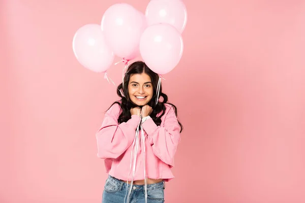 Excitada chica sosteniendo globos rosados, aislado en rosa - foto de stock