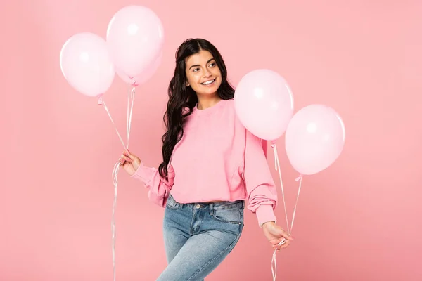 Красивая улыбающаяся девушка, держащая розовые шарики, изолированные на розовый — стоковое фото
