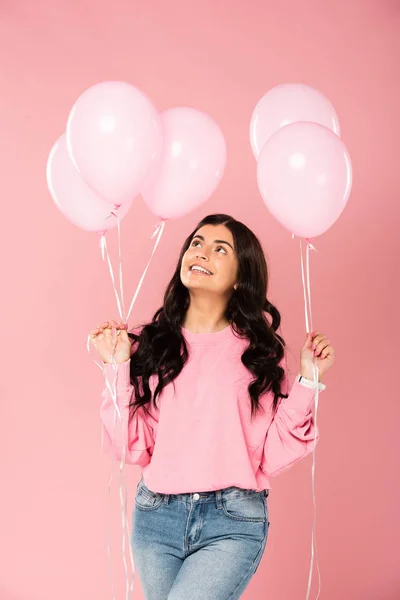 Красива весела дівчина тримає рожеві кульки, ізольована на рожевому — стокове фото