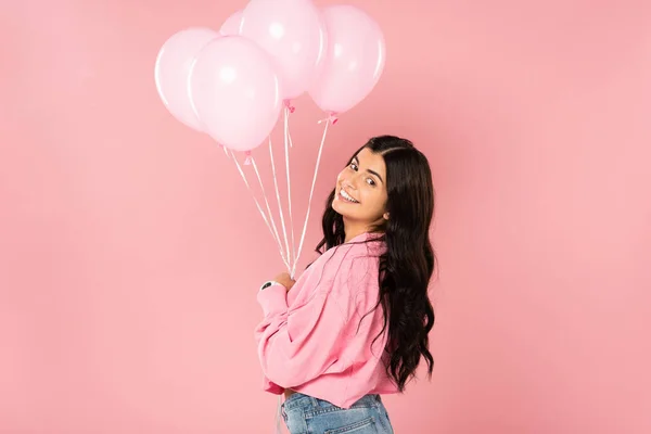 Красивая улыбающаяся девушка, держащая розовые шарики, изолированные на розовый — стоковое фото