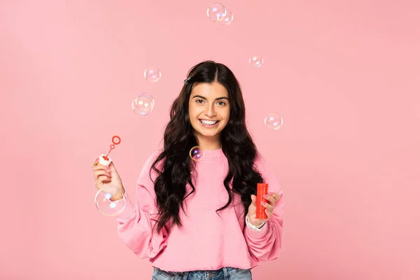 Happy beautiful girl blowing soap bubbles isolated on pink — Stock Photo