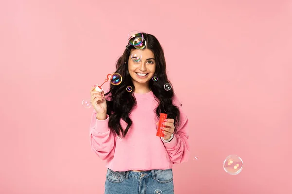 Smiling woman playing with soap bubbles isolated on pink — Stock Photo