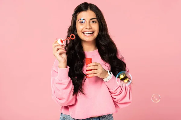 Beautiful brunette young woman playing with soap bubbles isolated on pink — Stock Photo