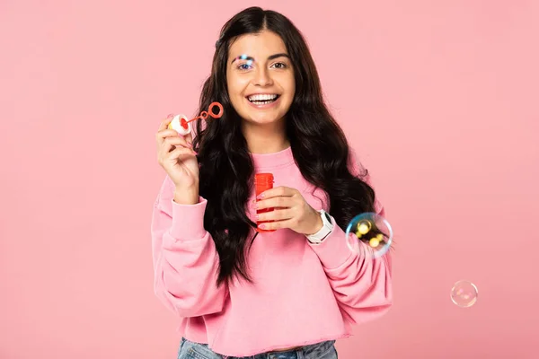 Bella bruna giovane donna che gioca con bolle di sapone isolate sul rosa — Foto stock