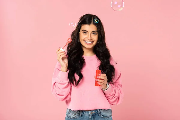 Pretty smiling girl playing with soap bubbles isolated on pink — Stock Photo