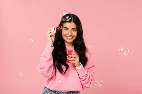 Bella giovane donna che gioca con bolle di sapone isolato su rosa — Foto stock