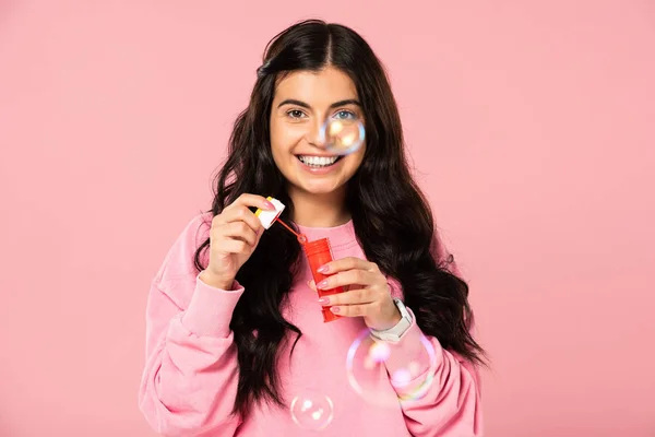 Brunette young woman playing with soap bubbles isolated on pink — Stock Photo