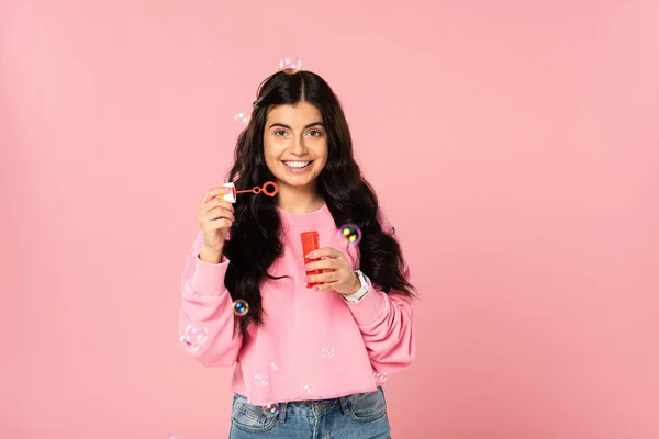 Smiling girl playing with soap bubbles isolated on pink — Stock Photo