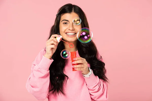 Cheerful girl playing with soap bubbles isolated on pink — Stock Photo