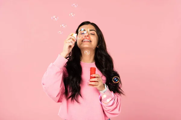 Funny girl blowing soap bubbles isolated on pink — Stock Photo