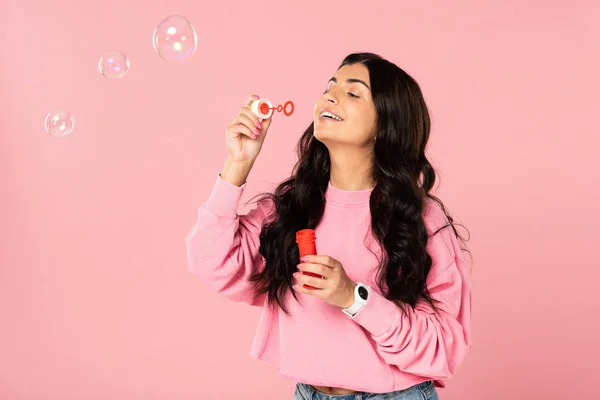 Bella ragazza bruna soffiando bolle di sapone isolato su rosa — Foto stock