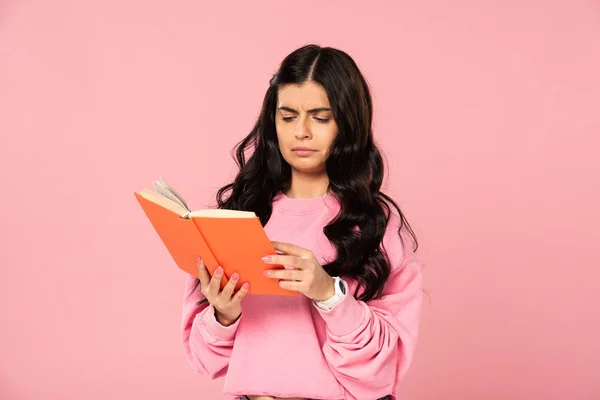 Confuso ragazza lettura libro, isolato su rosa — Foto stock