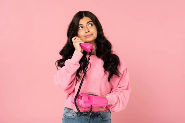 Nachdenkliches brünettes Mädchen spricht am Retro-Telefon isoliert auf rosa — Stockfoto