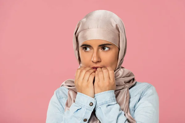 Hermosa chica musulmana asustada en hijab morder las uñas, aislado en rosa - foto de stock