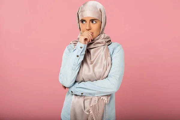 Estresado hermosa chica musulmana en hijab morder las uñas, aislado en rosa - foto de stock