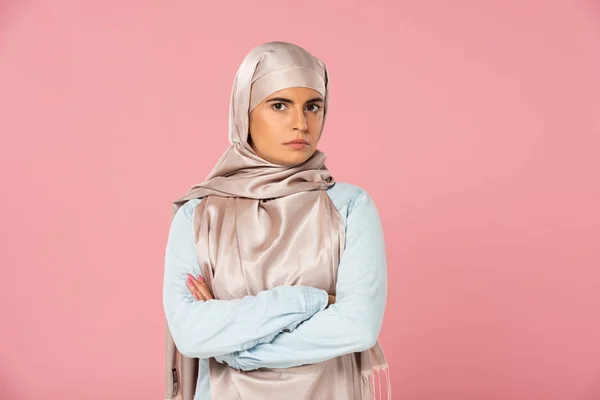Skeptical islamic woman in hijab with crossed arms, isolated on pink — Stock Photo