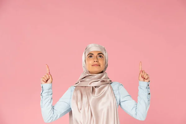 Belle femme islamique en hijab pointant vers le haut, isolée sur rose — Photo de stock