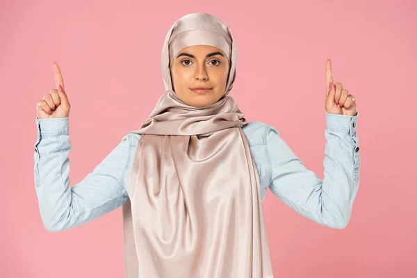 Jeune femme arabe en hijab pointant vers le haut, isolée sur rose — Photo de stock