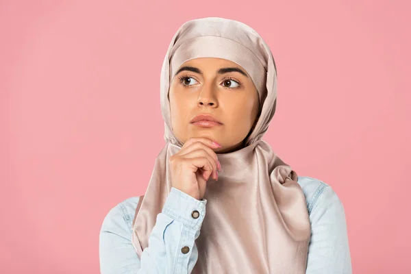 Attractive thoughtful muslim girl in hijab, isolated on pink — Stock Photo
