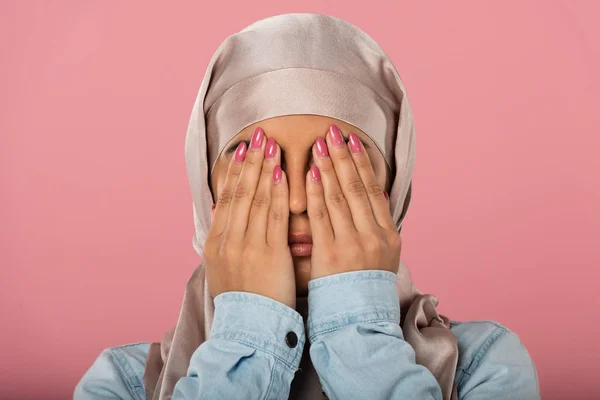 Chica musulmana asustada en hijab cerrando los ojos, aislado en rosa - foto de stock