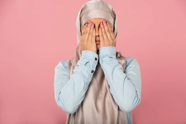 Hermosa chica musulmana asustada en hijab cerrando los ojos, aislado en rosa - foto de stock