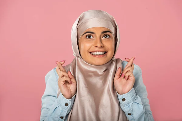 Femme musulmane gaie en hijab avec les doigts croisés, isolée sur rose — Photo de stock