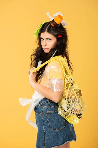 Bouleversé jeune femme avec des déchets dans les cheveux isolés sur jaune — Photo de stock