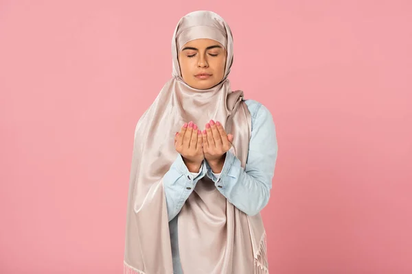 Attractive muslim woman in hijab praying isolated on pink — Stock Photo