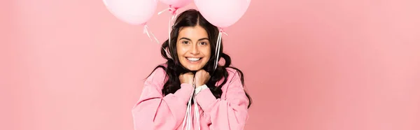 Aufgeregte brünette Frau mit rosa Luftballons, isoliert auf rosa — Stockfoto