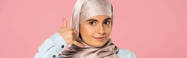Muslim girl in hijab showing call me sign, isolated on pink — Stock Photo