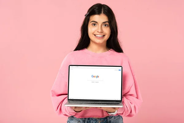 KYIV, UKRAINE - JULHO 30, 2019: menina sorridente segurando laptop com o site do Google na tela, isolado em rosa — Fotografia de Stock