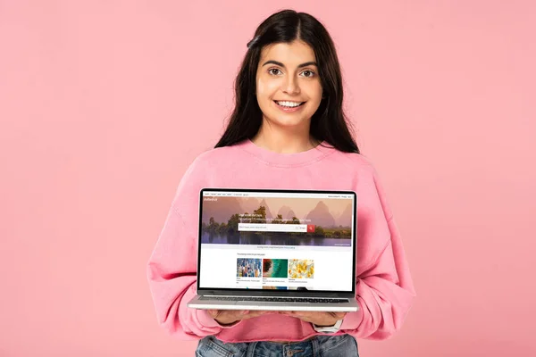KYIV, UKRAINE - JULHO 30, 2019: menina sorridente segurando laptop com site shutterstock na tela, isolado em rosa — Fotografia de Stock