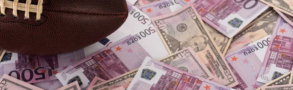 Plan panoramique de la balle de rugby sur les billets en euros et en dollars, concept de paris sportifs — Photo de stock
