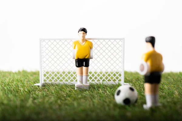 Селективный фокус игрушечных футболистов, ворот и мяча на зеленой траве, изолированной на белом, концепция ставок на спорт — стоковое фото