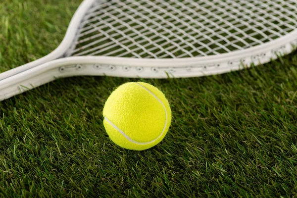 Raqueta de tenis y pelota sobre hierba verde, concepto de apuestas deportivas - foto de stock