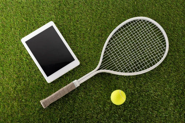 Vista dall'alto della racchetta da tennis e palla vicino al tablet digitale con schermo bianco su erba verde, concetto di scommesse sportive — Foto stock