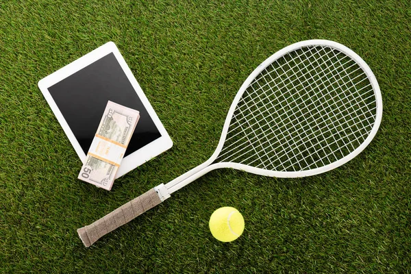 Top view of tennis racket and ball near digital tablet and euro banknotes on green grass, sports betting concept — Stock Photo