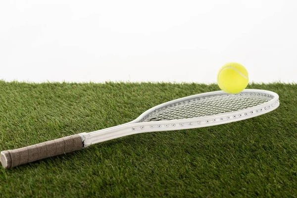 Raqueta de tenis y pelota en césped verde aislado en blanco, concepto de apuestas deportivas - foto de stock