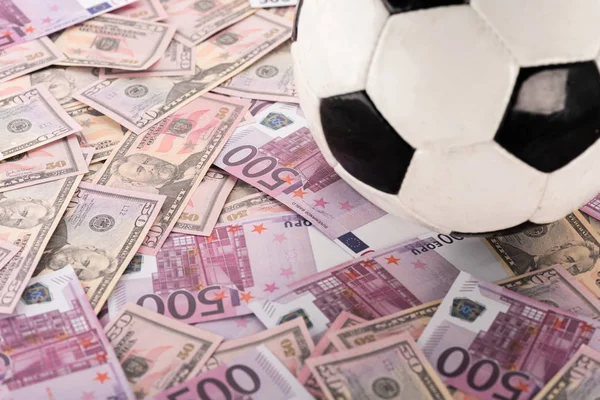 Крупный план футбольного мяча на банкнотах евро и доллара, концепция ставок на спорт — стоковое фото