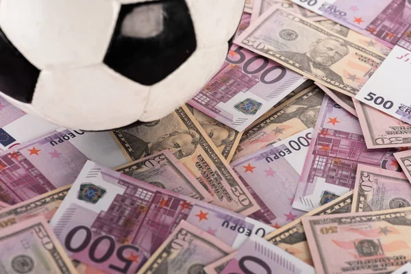 Vista de cerca de la pelota de fútbol en billetes de euro y dólar, concepto de apuestas deportivas - foto de stock