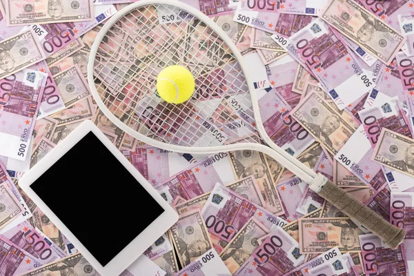 Vista superior de la tableta digital con pantalla en blanco, raqueta de tenis y pelota en euros y billetes de dólar, concepto de apuestas deportivas - foto de stock