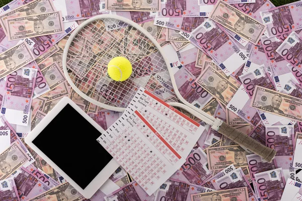 Vista dall'alto di tablet digitale, liste scommesse, racchetta da tennis e palla su banconote in euro e dollaro, concetto di scommesse sportive — Foto stock
