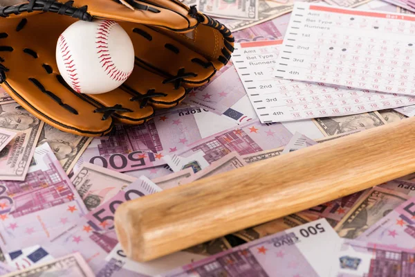 Betting lists near baseball bat, glove and ball on euro and dollar banknotes, sports betting concept — Stock Photo