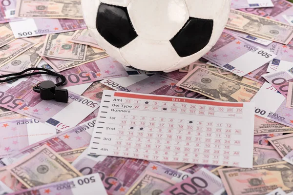 Bola de futebol, apito e lista de apostas em notas de euro e dólar, conceito de apostas desportivas — Fotografia de Stock