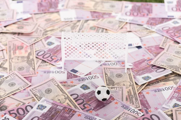 Portones de fútbol de juguete y pelota en billetes de euro y dólar, concepto de apuestas deportivas - foto de stock