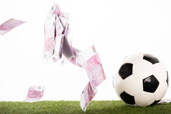 Balón de fútbol cerca de billetes en euros voladores aislados en blanco, concepto de apuestas deportivas - foto de stock