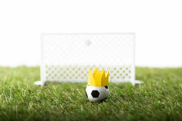 Вибірковий фокус іграшкових футбольних воріт і м'яча з паперовою короною на зеленій траві ізольовані на білому, концепція спортивних ставок — стокове фото