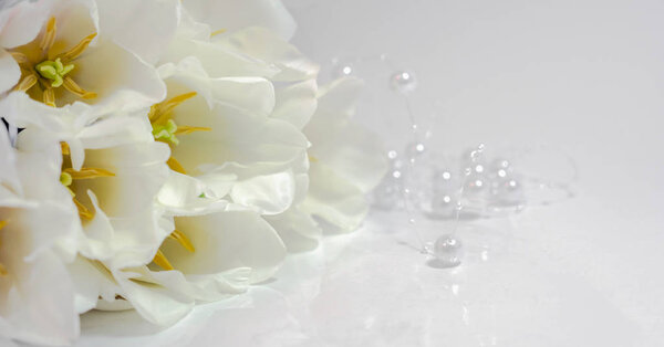Bouquet of white tulips with white beads on a white table