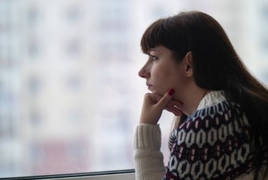 kadın uzun saçlı düşünceli pencere yakın çekim, evlerin arka planı görünüyor